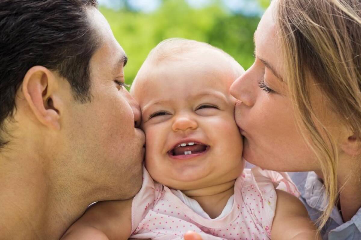 genitori che baciano la figlia